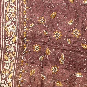 May include: A brown fabric with a white and gold embroidered floral pattern. The fabric has a subtle texture and a delicate design.