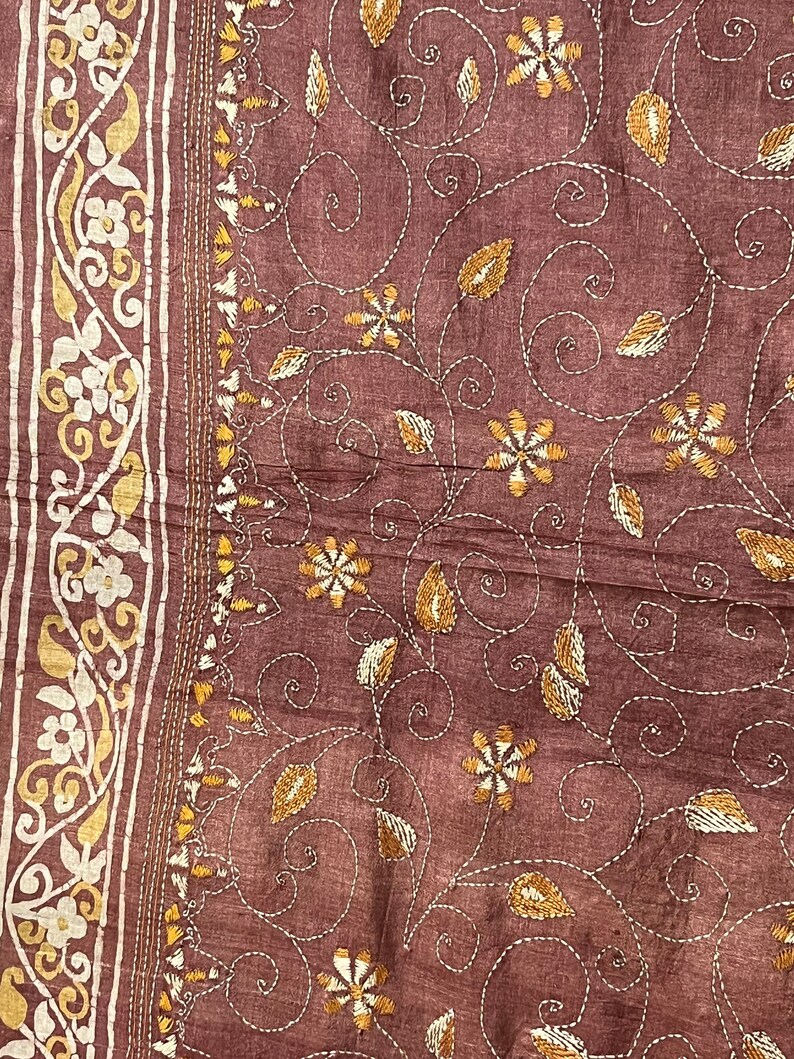 May include: A brown fabric with a white and gold embroidered floral pattern. The fabric has a subtle texture and a delicate design.