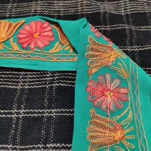 May include: Teal fabric trim with gold and pink embroidered floral designs. The trim features a repeating pattern of flowers and leaves.