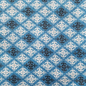 May include: Blue fabric with a white and black geometric pattern. The pattern is a repeating diamond shape with a stylized floral design in the center.