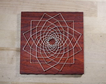 May include: A geometric design created with string art on a dark red wooden board. The design is a series of concentric squares with lines connecting the corners.