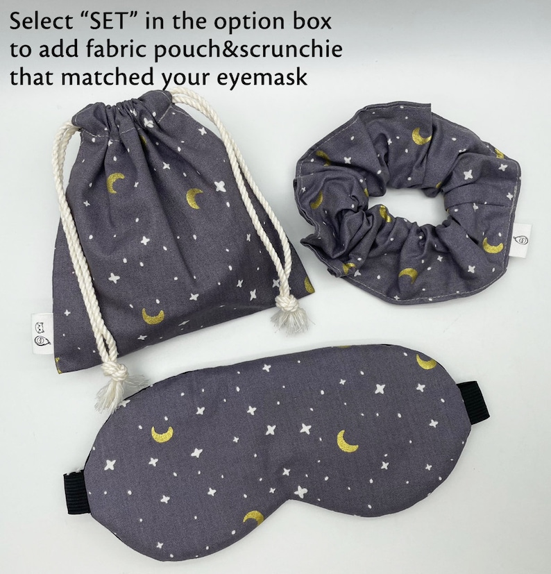 Puede incluir: Un conjunto de antifaz, coletero y bolsa con cord&oacute;n grises. La tela presenta un estampado de lunas doradas y estrellas blancas. El antifaz tiene una banda el&aacute;stica negra. El texto de la imagen dice: "Select SET in the option box to add fabric pouch&scrunchie that matched your eyemask."
