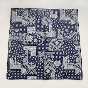 Puede incluir: Un pa&ntilde;uelo cuadrado con fondo azul marino oscuro y estampado de patchwork blanco. El dise&ntilde;o consta de secciones geom&eacute;tricas repetitivas, intrincados motivos de cachemira y peque&ntilde;os patrones de lunares dispuestos en una cuadr&iacute;cula.