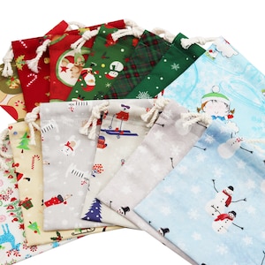 May include: A set of ten Christmas-themed drawstring bags in various colours and patterns. The bags feature designs of snowmen, candy canes, snowflakes, and other wintery motifs.