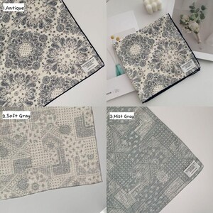 May include: A collection of three square fabric handkerchiefs featuring intricate paisley and mandala-inspired patterns. The first is cream with dark gray details, the second is light gray, and the third is a muted mist gray, each with a small white label.