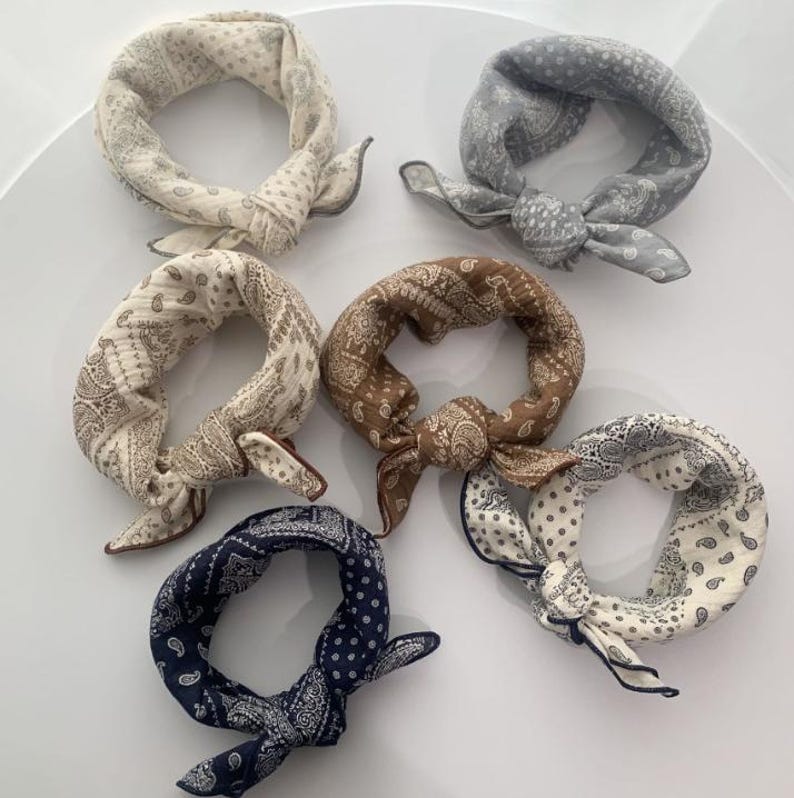 Puede incluir: Seis pa&ntilde;uelos cuadrados atados en formas circulares, con varios patrones de cachemira y florales en tonos crema, gris claro, beige, marr&oacute;n, azul oscuro y blanco. Cada pieza de tela muestra motivos intrincados y extremos anudados.