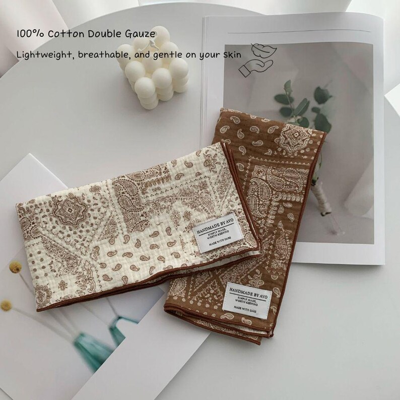 May include: Two folded cotton double gauze cloths featuring a brown and cream paisley pattern. Each cloth has a white rectangular label stitched on the corner that reads HANDMADE BY AVO, SIMPLY MADE, WORTH KEEPING, MADE WITH CARE.