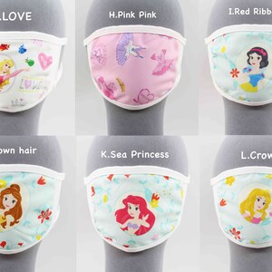 May include: Six different fabric face masks with white trim, each featuring a different Disney princess. The masks are displayed on a gray surface. The masks feature princesses such as Cinderella, Snow White, Belle, Ariel, and more.