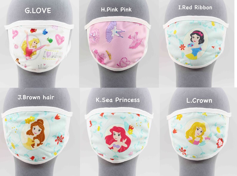 May include: Six different fabric face masks with white trim, each featuring a different Disney princess. The masks are displayed on a gray surface. The masks feature princesses such as Cinderella, Snow White, Belle, Ariel, and more.