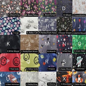 Puede incluir: Una colecci&oacute;n de muestras de tela con varios patrones. Los dise&ntilde;os incluyen flores, osos, gatos, paisley, ratones, espacio y caras sonrientes. Cada muestra est&aacute; etiquetada con una letra y un nombre descriptivo, como "Blooming" y "Happy Mouse."
