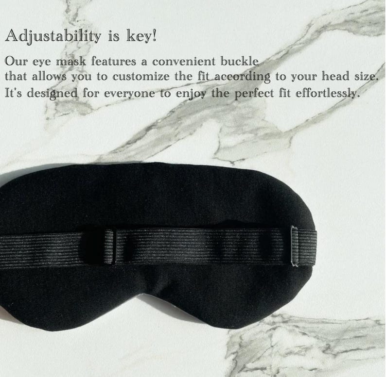 Op de afbeelding: Zwarte oogmasker met een verstelbare band en gesp. De band is gemaakt van zwart elastiek en heeft een gespsluiting. Het masker is ontworpen om licht te blokkeren en een comfortabele pasvorm te bieden.