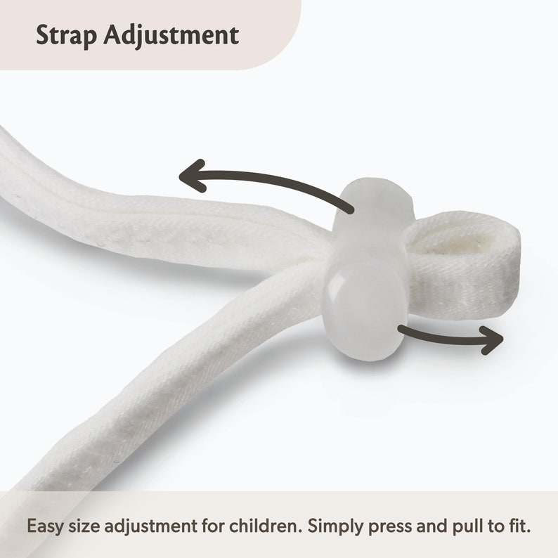 Op de afbeelding: Een witte stoffen band met een doorzichtige plastic verstelknop. De afbeelding bevat de tekst Strap Adjustment en Easy size adjustment for children. Simply press and pull to fit, met donkere pijlen die de beweging van de verstelknop aangeven.