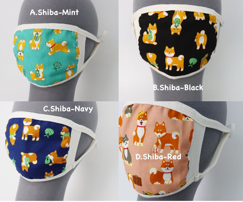 Op de afbeelding: Vier stoffen mondkapjes met Shiba Inu-hondenpatronen in mintgroen, zwart, marineblauw en rood. Elk masker heeft een witte rand en elastische oorlussen. De tekstlabels A.Shiba-Mint, B.Shiba-Black, C.Shiba-Navy en D.Shiba-Red zijn zichtbaar.