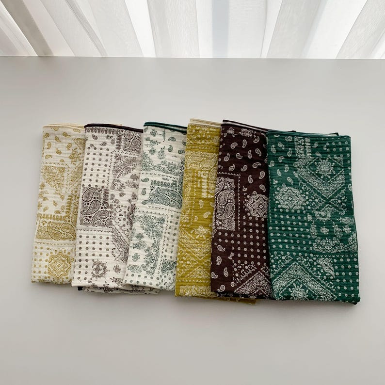 Puede incluir: Un conjunto de seis pa&ntilde;os de tela rectangulares con textura acolchada y un patr&oacute;n de bandana de cachemira repetitivo. Los pa&ntilde;os est&aacute;n dispuestos uno al lado del otro en una fila, mostrando una paleta de colores crema, beige, verde oliva, marr&oacute;n oscuro y verde bosque.