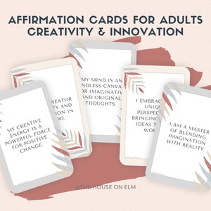 May include: Five affirmation cards with a light grey background and a design of stylised leaves in shades of red, blue, and grey. The text on the cards reads: "My creative energy is a powerful force for positive change." "Creator, ty and ion in 00." "My mind is an endless canvas for imaginative and original thoughts." "I embrace unique perspectives, bringing ideas to life." "I am a master of blending imagination with reality."
