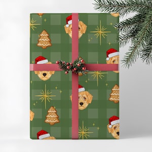 May include: Wrapped gift with green plaid wrapping paper featuring illustrations of dogs wearing Santa hats and gingerbread Christmas trees. The gift is tied with a red ribbon and decorated with a sprig of berries and pine needles.