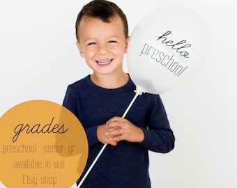 May include: A young boy is holding a white balloon with the text "hello preschool" printed on it. A yellow circle with the text "grades preschool - senior yr. available in our Etsy shop" is in the bottom left corner of the image.