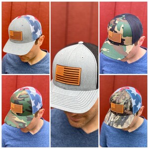 May include: Four different baseball caps with a leather American flag patch on the front. The caps are in different color combinations of grey, black, camouflage, and blue.