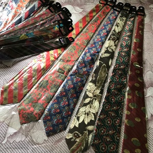 May include: A collection of colorful silk ties with various patterns, including paisley, floral, and geometric designs. The ties are packaged in clear plastic bags and are ready to be worn.