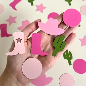 May include: Pink and green paper cutouts of cowboy hats, boots, stars, cacti, and circles. These cutouts are perfect for party decorations or scrapbooking.