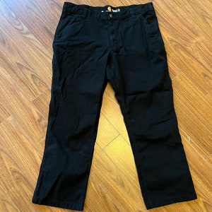 May include: Black work trousers with a straight fit and a Carhartt label on the waistband.