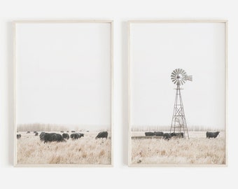 May include: A set of two framed prints featuring a minimalist landscape with a windmill and cattle. The prints are in a white frame and have a white background.