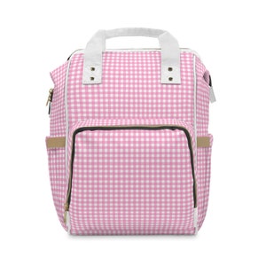 K&ouml;nnte beinhalten: Rosa-wei&szlig;e Gingham-Wickeltasche mit gro&szlig;em Frontfach und zwei Seitentaschen.