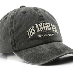 Puede incluir: Una gorra de béisbol negra de estilo vintage con el texto "Los Angeles" bordado en blanco en la parte delantera. El texto "Vintage Made" también está bordado en blanco debajo del nombre de la ciudad.