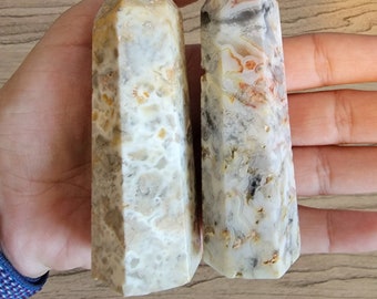 May include: Two white agate crystal points with brown and orange inclusions. The points are polished and have a smooth, glassy finish.