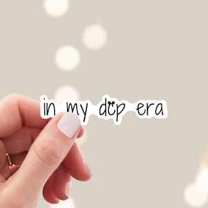 May include: A white sticker with the text "in my dcp era" written in black.