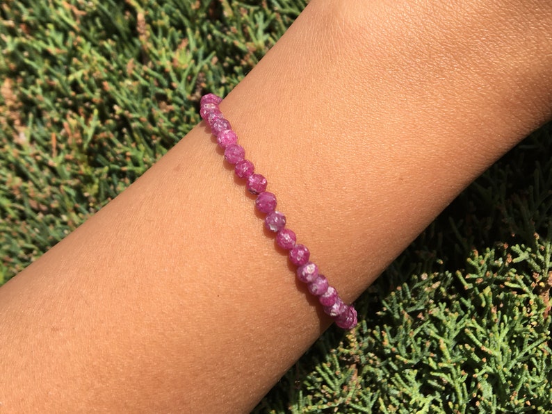 Dainty ruby beaded bracelet with deep red faceted gemstones and small gold spacer beads on an adjustable cord — handmade gemstone jewelry for women, elegant stacking bracelet or solitaire statement piece.