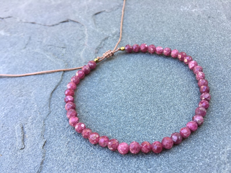 Dainty ruby beaded bracelet with deep red faceted gemstones and small gold spacer beads on an adjustable cord, handmade gemstone jewelry for women, elegant stacking bracelet or solitaire statement piece.