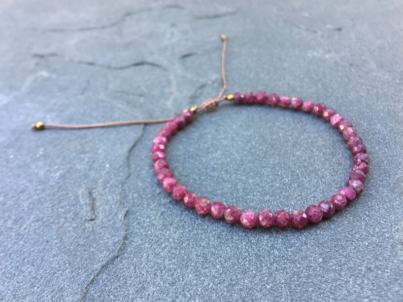 Dainty ruby beaded bracelet with deep red faceted gemstones and small gold spacer beads on an adjustable cord — handmade gemstone jewelry for women, elegant stacking bracelet or solitaire statement piece.