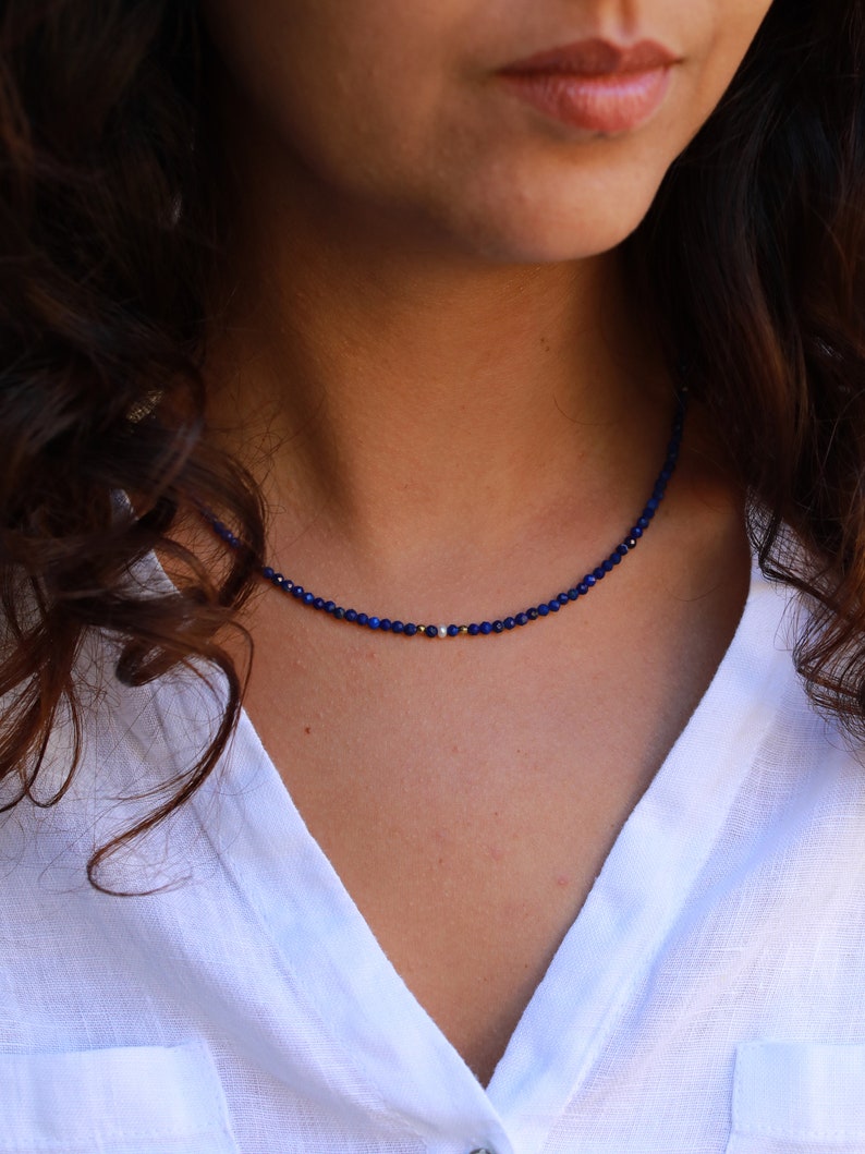 Lapis lazuli beaded necklace with 3mm faceted navy blue beads and a white pearl in the middle. There are 2mm gold hematite beads at each side of the pearl. The necklace has gold clasp and extender chain.