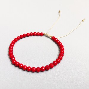 Dainty red coral beaded bracelet with adjustable cord, featuring vibrant natural coral gemstones.