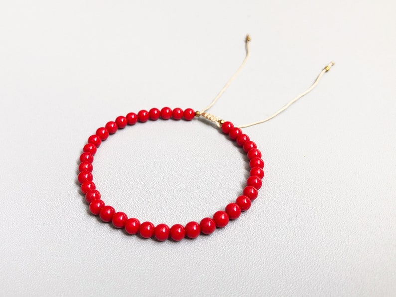 Dainty red coral beaded bracelet with adjustable cord, featuring vibrant natural coral gemstones.