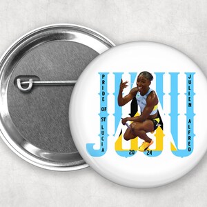 May include: A white button with a blue and yellow design. The design features the text "JAU" with the words "PRIDE OF ST LUCIA" and "JULIEN ALFRED" on either side. The button also features a photo of a woman athlete in a blue and yellow uniform.