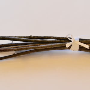 May include: A bundle of thin, brown twigs tied together with a white ribbon.
