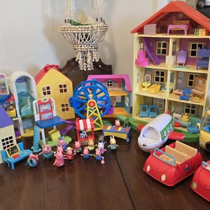 Puede incluir: Colección de juegos de juguetes coloridos, que incluyen una casa de muñecas de varios pisos, una noria y varios vehículos. El conjunto también presenta varias figuras pequeñas, todas dispuestas sobre una superficie de madera.