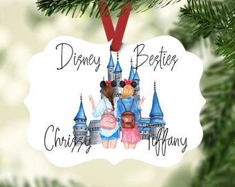 Puede incluir: Adorno blanco con una ilustración de castillo azul y blanco, dos chicas con mochilas y el texto "Disney Besties" en la parte superior y "Chrissy" y "Tiffany" en la parte inferior.