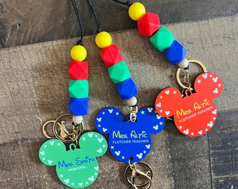 May include: Three colorful Mickey Mouse-shaped keychains with different titles. The top keychain is red and says "Mrs. Altic Fletcher Teacher". The middle keychain is blue and says "Mrs. Altic Fletcher Teacher". The bottom keychain is green and says "Mrs. Smith Principal".