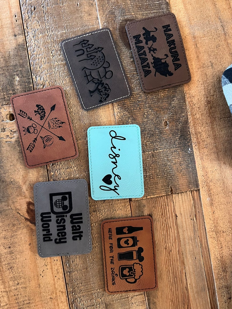 May include: Six brown leather patches with various Disney-themed designs, including "Hakuna Matata", "Walt Disney World", "Disney", and "Here for the Drinks".