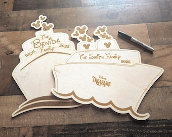 May include: Two wooden cruise ship-shaped signs with engraved text, including "The Benida Family 2025" and "The Smith Family 2025". The signs feature Mickey Mouse head cutouts and the words "Dream" and "Disney Treasure". A black marker is also present.