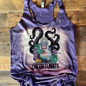 Op de afbeelding: Paarse tanktop met een ontwerp met bleekmiddelspatten met Ursula uit De Kleine Zeemeermin. Het ontwerp bevat Ursula's tentakels, een groene zeeslang en een kristallen bol. De tekst "You poor unfortunate soul" is onder de afbeelding gedrukt.