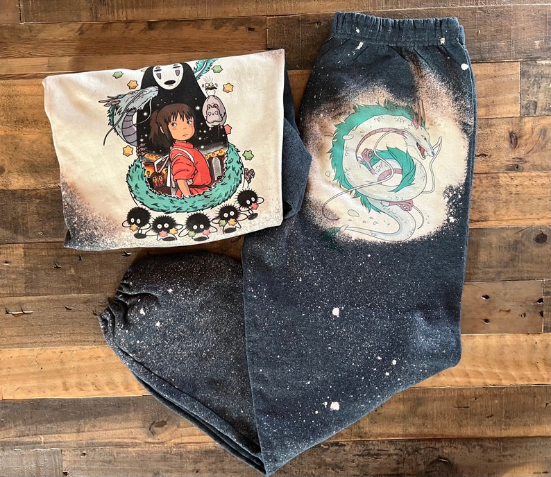 May include: A black and white graphic print of a dragon and a girl with a white background on a black and white sweatshirt. The sweatshirt has a distressed look with white splatter paint.