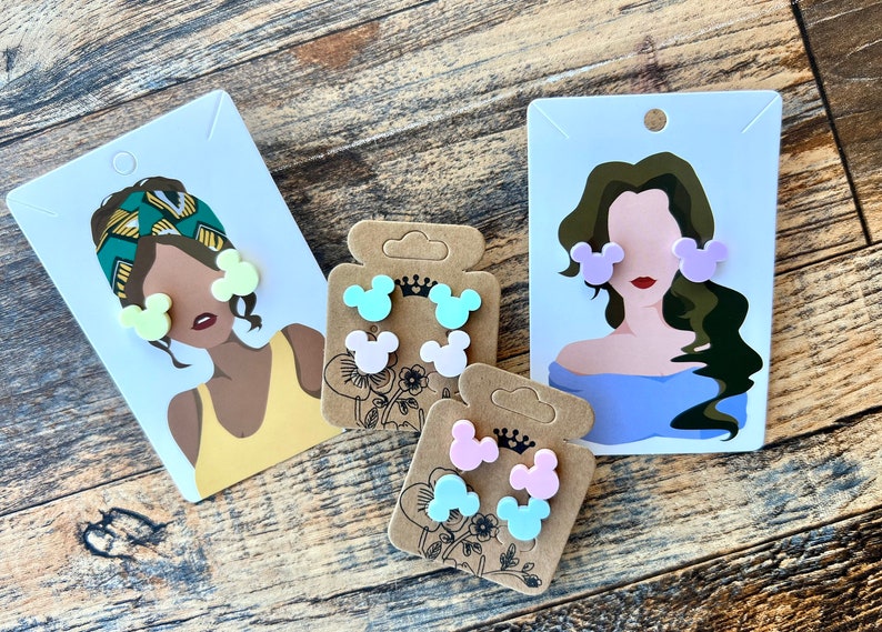 May include: Three sets of colorful Mickey Mouse-shaped earrings. Each set features two earrings in a different pastel color: light green, pink, and light blue.