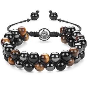 Op de afbeelding: Een armband met twee rijen zwarte en bruine kralen. De armband heeft een zilveren sluiting met een symbool. De armband is gemaakt van natuurlijke stenen.