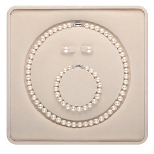 Può includere: Un set di gioielli di perle bianche in una scatola color crema. Il set comprende una collana, un braccialetto e orecchini.