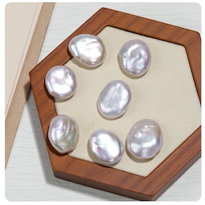 May include: Seven white baroque pearls on a wooden display stand. The pearls are various sizes and shapes.