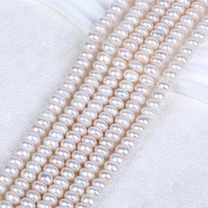 May include: A strand of white freshwater pearls, with a smooth, round shape. The pearls are strung together on a clear thread, and they are all approximately the same size.